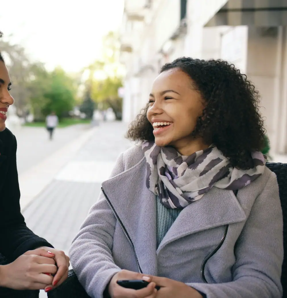 Two women laughing over coffee at a café table