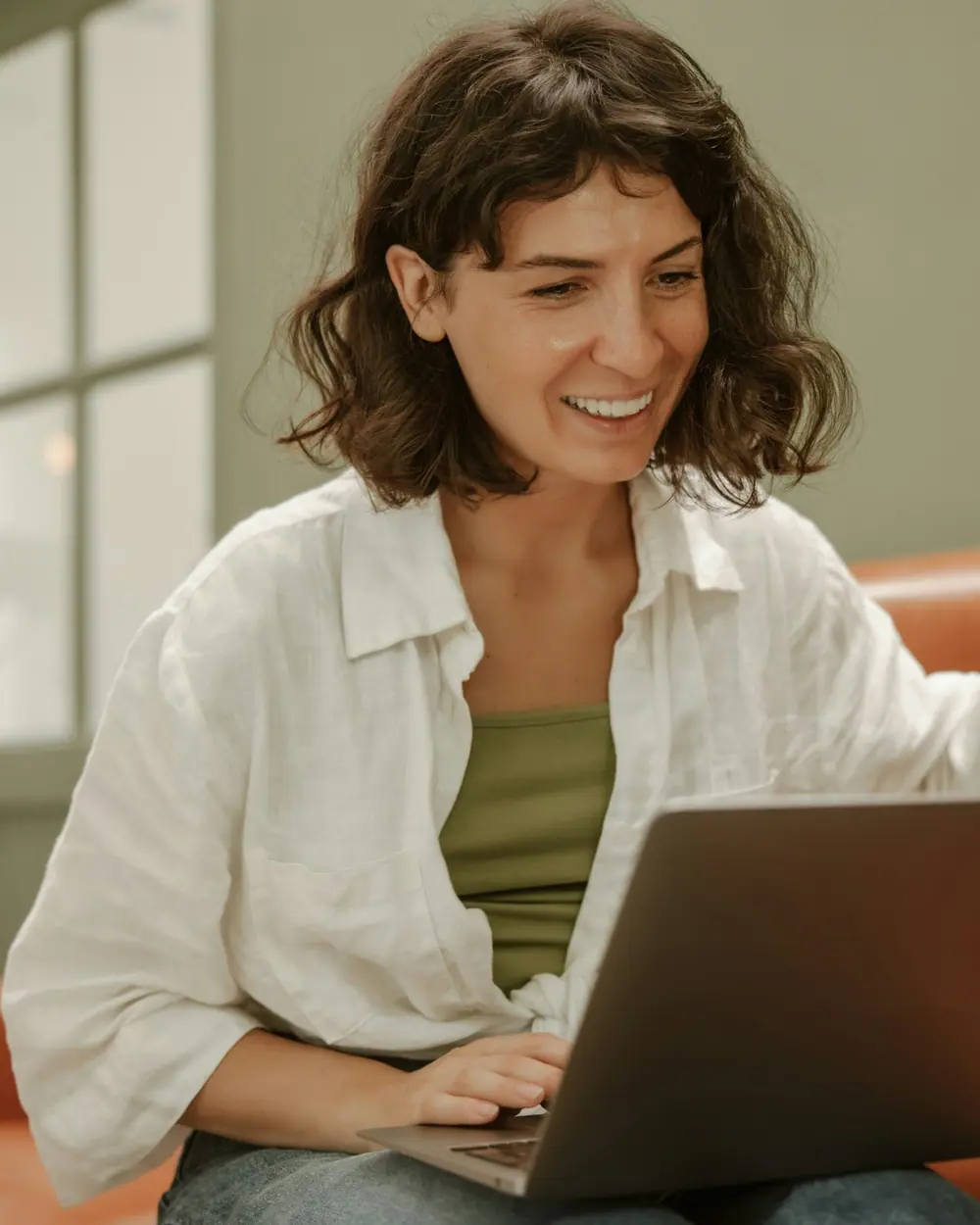 A woman waving and smiling at a video call on her laptop